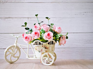 Yapay pembe gül bisikletler üzerinde masa üzerinde beyaz arka planda izole edilmiş buket kova bisiklet şenlikli arka plan için yumuşak tonlu bisiklet ya da Sevgililer Günü romantizmi için duvar kâğıdı kopya alanı 