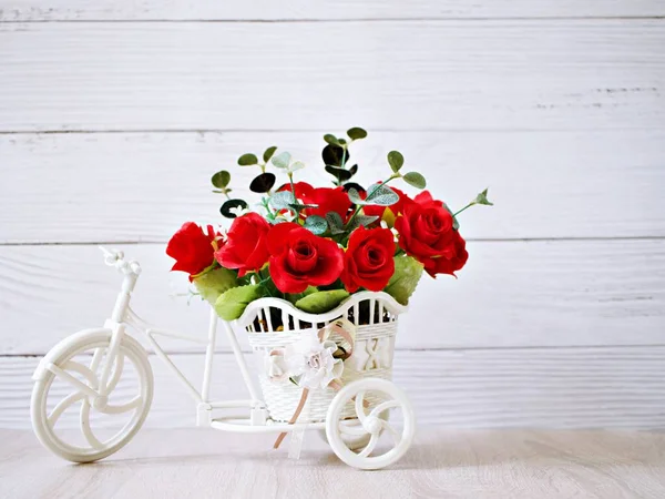 Artificial red rose flowers in bike toy on table bouquet bucket Bicycle with soft tone for festive background or wallpaper copy space for lettering ,Valentine\'s day romantic love ,birthday card