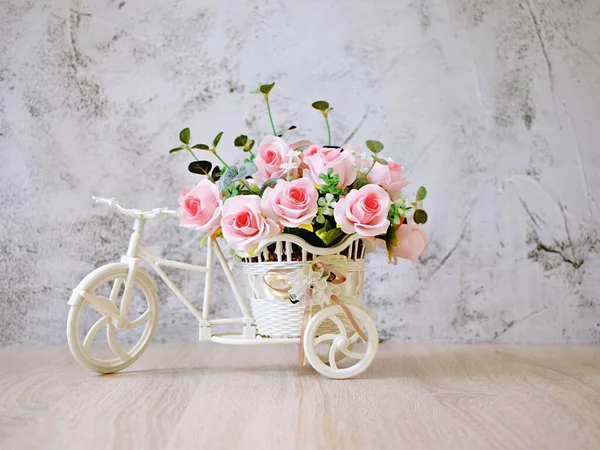 Yapay pembe gül bisikletler üzerinde masa üzerinde beyaz arka planda izole edilmiş buket kova bisiklet şenlikli arka plan için yumuşak tonlu bisiklet ya da Sevgililer Günü romantizmi için duvar kâğıdı kopya alanı 