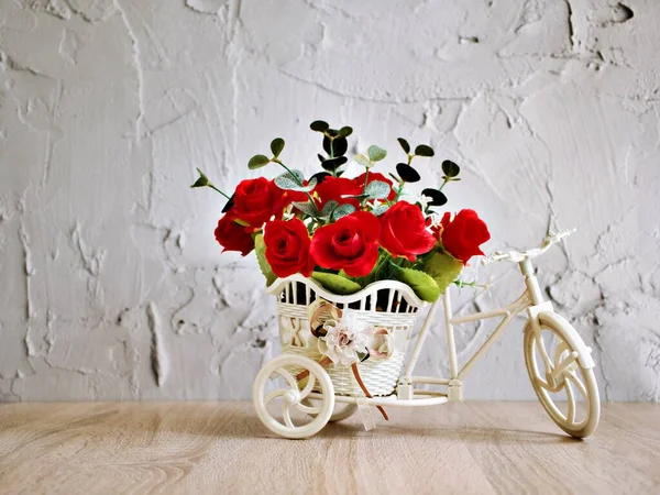 Artificial red rose flowers in bike toy on table bouquet bucket Bicycle with soft tone for festive background or wallpaper copy space for lettering ,Valentine\'s day romantic love ,birthday card