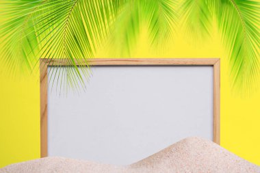 Kumsalda, sarı duvarlı ve palmiye yapraklı boş bir çerçeve. Turizm için kart ya da poster. Tatil tatili, tropik seyahat, doğa okyanusu. Yaz tatili konsepti.