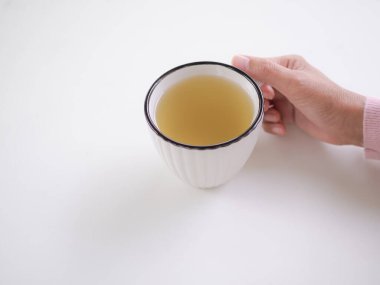 Beyaz fincanda limon çayı. Beyaz ahşap masada sıcak çay içen el kadını. Bitkisel meyve. iyi sağlık konsepti için yiyecek.