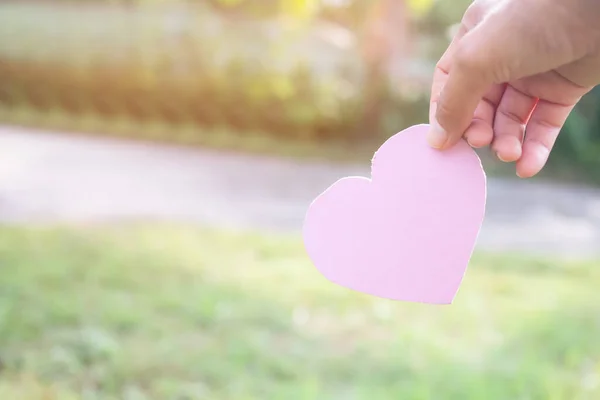 Hand Holding Pink Heart Shape Paper Green Nature Background Card — Stockfoto