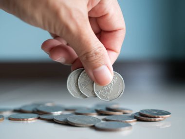 Stack coin.closeup finger woman holding money with blur pile cash on blue background.bank currency Thai. plan income investment growth and saving for 2023 new year.business or treasury finance concept