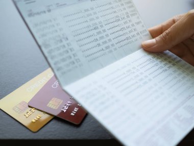 Finger holding Book Bank with Credit Card on table background,Technology Electronic Ecommerce,Plan Investment Income and Saving money Cash for 2023 New Year,Business and Finance concept.