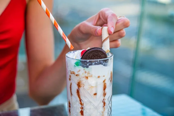 Flickan använder en milkshake med grädde, sötsaker, kakor och våffla — Stockfoto
