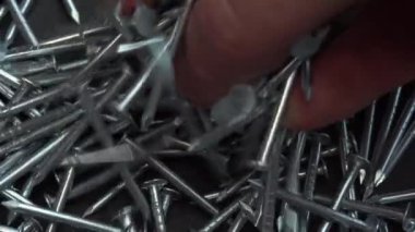 El inşaat işi için metal çivi alıyor, çiviler yakın arka planda dönüyor, çivi ya da çiviler inşaat işi için.