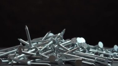 İnşaat işleri için metal çiviler siyah arka planda dönen bir zemine düşüyor, çiviler yakın arkaplanda dönüyor, inşaat işleri için çivi ya da çivi çakılıyor