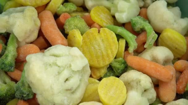 Φρέσκα κατεψυγμένα λαχανικά που πέφτουν σε περιστρεφόμενο φόντο, υγιεινά τρόφιμα ή διαιτητικά τρόφιμα για χορτοφάγους και vegans, κατεψυγμένα κουνουπίδια, μπρόκολα και καρότα για βρέφη — Αρχείο Βίντεο