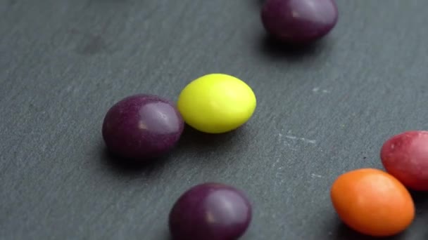 Gekleurde fruit snoepjes scatter op een zwarte achtergrond, gekleurde marco snoepjes — Stockvideo