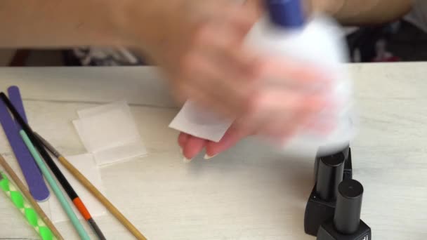 Девушка обезжиривает ногти специальной жидкостью перед нанесением лака для ногтей, готовя ногти к маникюру — стоковое видео