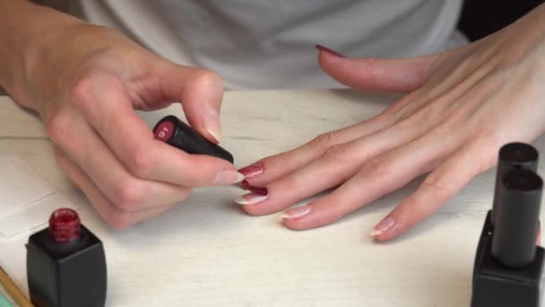 Chica aplica esmalte de uñas rojo a sí misma, auto manicura — Vídeos de Stock