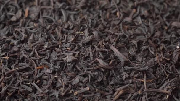 Fundo para um café ou restaurante, chá de folhas soltas preto polvilhado em um prato e girando de perto, publicidade chá — Vídeo de Stock