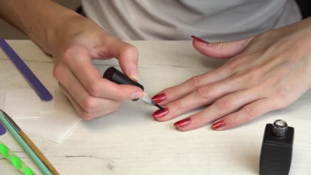 Gadis membuat dirinya manikur dan cat kukunya dengan cat kuku merah dengan berkilau — Stok Video