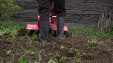 Çiftçi tarlayı bir benzin ekicisiyle işliyor, sebze yetiştirmek için bir bahçe hazırlıyor.