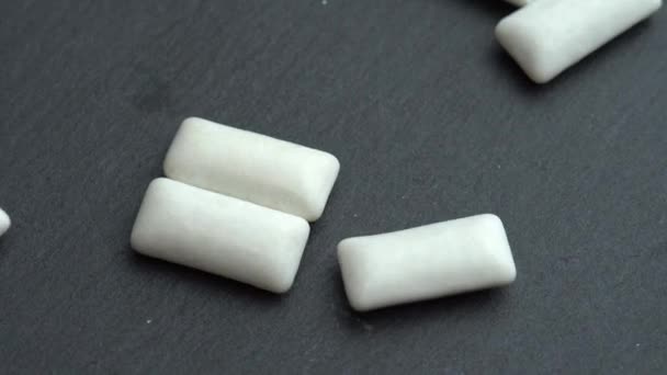 Almofadas de goma de mascar de hortelã branca espalhadas no fundo preto rotativo, almofadas de goma de mascar — Vídeo de Stock