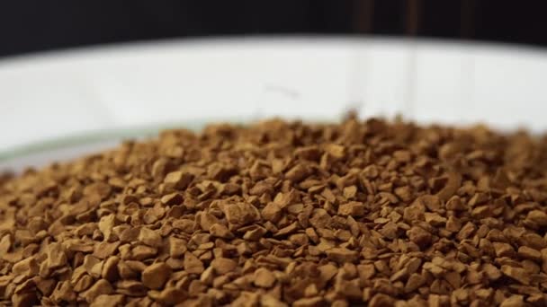 Granuli di caffè istantaneo spruzzato su un piatto primo piano filatura come sfondo per una caffetteria, granulato commerciale caffè, tifo mattina — Video Stock