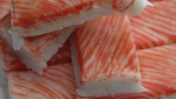 Krab sticks draaien op een bord als achtergrond, heerlijk en sappig krab vlees draait op een bord, krab planken — Stockvideo