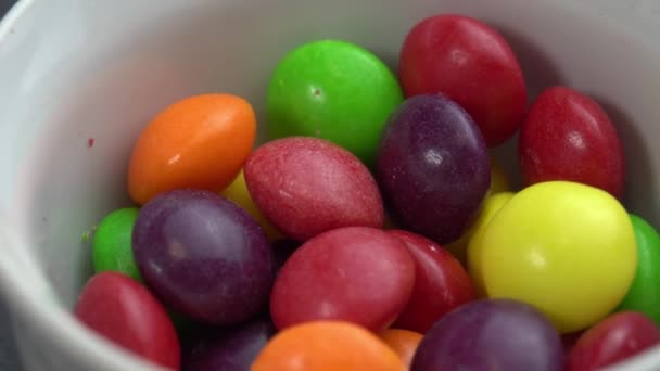 Doces de frutas coloridas giram em um fundo preto, doces marco coloridos — Vídeo de Stock