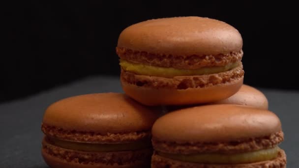 Macaroon doces girar em uma superfície preta para o fundo, doces estão girando macro — Vídeo de Stock