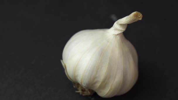 Garlic spinning on black background, close shot of an garlic solwly rotating on a black background — Stock Video
