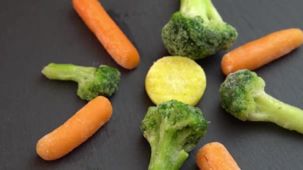 Alimentos saludables o alimentos dietéticos para vegetarianos y veganos, verduras frescas congeladas que giran sobre fondo negro, coliflor congelada, brócoli y zanahorias bebé — Vídeo de stock
