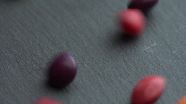 Doces de frutas coloridas se espalham em um fundo preto, doces marco coloridos — Vídeo de Stock