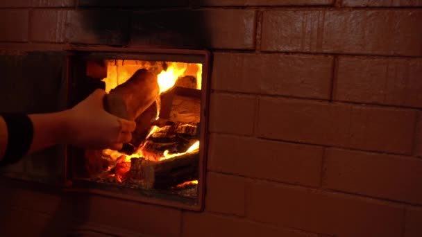 Hand legt Brennholz in den Ofen, Flammenzungen in den rustikalen Ofen — Stockvideo