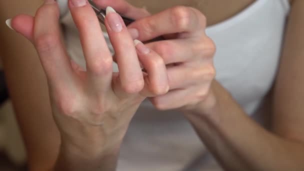 Meisje snijdt nagelriemen in de buurt van nagels met nippers, het voorbereiden van nagels voor het aanbrengen van nagellak, zelf manicure — Stockvideo