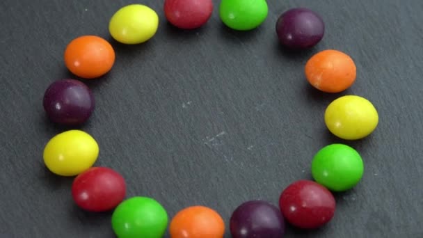 Doces coloridos giram em um fundo preto e a mão leva um doce, doces coloridos — Vídeo de Stock