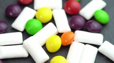 Şekerler renkli şekerlemeler ve nane çiğneme yastıkları, renkli tatlılar siyah bir tabakta dönüyor.