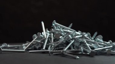 İnşaat işleri için metal çiviler siyah arka planda dönen bir zemine düşüyor, çiviler yakın arkaplanda dönüyor, inşaat işleri için çivi ya da çivi çakılıyor