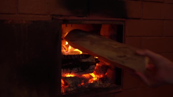 Hand legt Brennholz in den Ofen, Flammenzungen in den rustikalen Ofen — Stockvideo