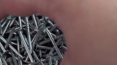 El inşaat işi için metal çivi alıyor, çiviler yakın arka planda dönüyor, çivi ya da çiviler inşaat işi için.