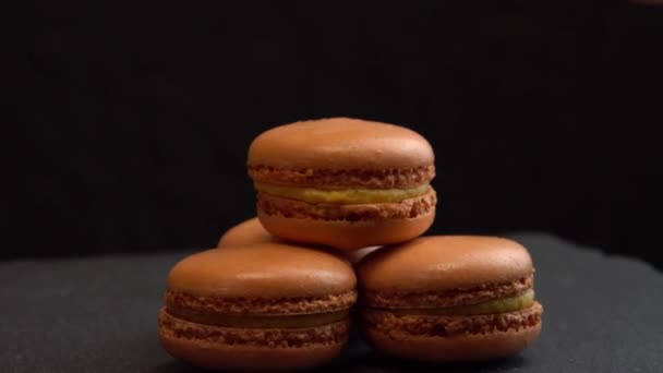 Macaroon cukorka forog a fekete felületen a háttér, édességek forog makró — Stock videók
