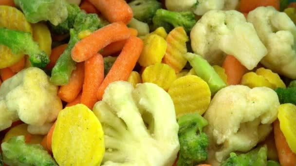 Verduras frescas congeladas que caen sobre un fondo giratorio, alimentos saludables o alimentos dietéticos para vegetarianos y veganos, coliflor congelada, brócoli y zanahorias bebé — Vídeo de stock