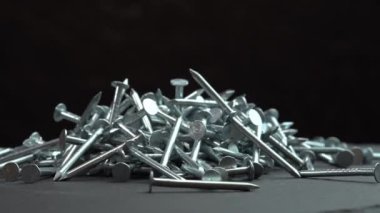 Hobnail 'ler yakın plan örüyor, inşaat işleri için metal çiviler, inşaat işleri için siyah arkaplan, çivi ya da çiviyle yüzey üzerinde dönüyor