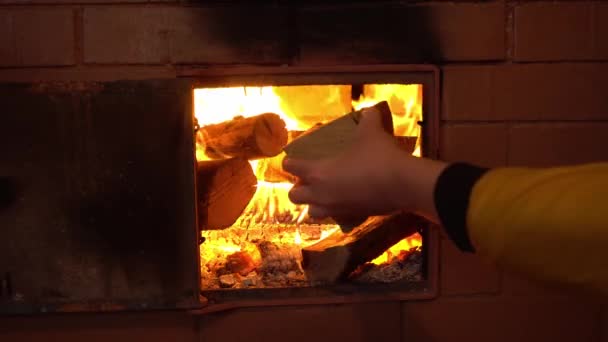 Hand zet brandhout in de oven van de kachel, tongen van vlam in de rustieke kachel — Stockvideo