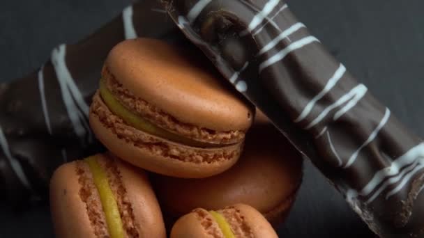 Čokoláda a makrón otáčet na černém pozadí, chutné bonbóny, sladkosti jsou točí makro — Stock video