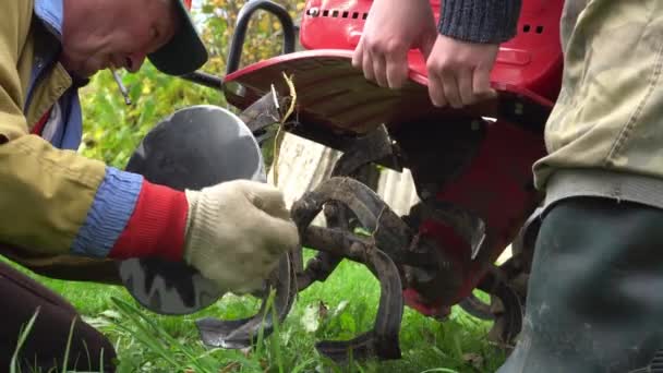 Montera en kultivator istället för hjul på ett monoblock, bonden odlar marken med en bensinodlare, förbereda en grönsaksträdgård för plantering — Stockvideo