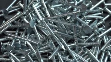 İnşaat işleri için metal çiviler dönen bir yüzeye düşüyor, çiviler yakın arkaplanda dönüyor, inşaat işleri için çivi ya da çivi çakılıyor