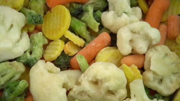 Dönen arka planda düşen taze donmuş sebzeler, vejetaryenler ve vejetaryenler için sağlıklı gıda veya diyet yiyecekler, donmuş karnabahar, brokoli ve bebek havuçları — Stok video