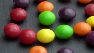 Renkli meyve şekerlemeleri siyah arka planda döner, renkli Marco Sweets