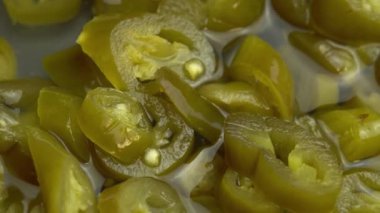 Dilimlenmiş jalapeno biberleri arka plan olarak döner, yakın plan acı biber turşusu.
