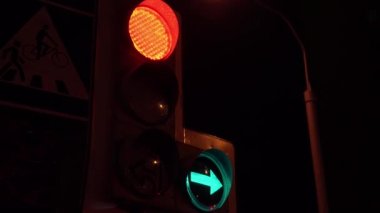 Kırmızı ışıklı ve yeşil oklu trafik ışıkları sağ ve solu gösteriyor, el kameralı. Siyah gökyüzünün arka planındaki trafik ışıklarını kapat.