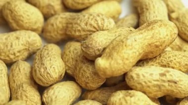 Yer fıstıkları tepeden tırnağa bir tabağa dökülür. Yer fıstığı. Yer fıstıkları arka plan olarak döner, kabuklu fıstıklar