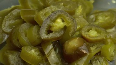Dilimlenmiş jalapeno biberleri arka plan olarak döner, yakın plan acı biber turşusu.