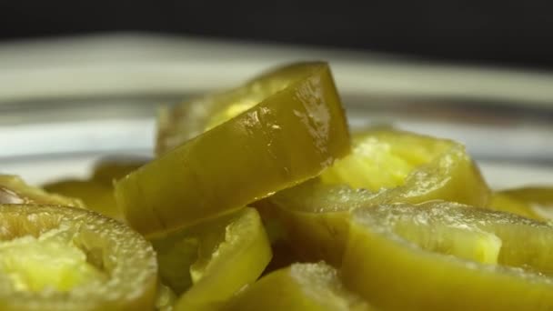 Nakrájené nakládané papričky jalapeno otáčet na talíři jako pozadí, zblízka nakládané chilli papričky jalapeno — Stock video