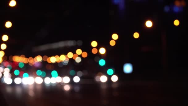 Runde farverige bokeh skinne fra billys i trafikprop på byens gade. Smuk glitrende bokeh i mørk sløret baggrund om natten. Abstrakt koncept. Reflekterer ensom hovedstad livsstil. – Stock-video