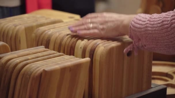 Muchas tablas de cortar en la feria y la vendedora pone su mano sobre ellas — Vídeos de Stock